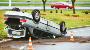 Car crash accident on a street with an overturned, damaged vehicle. 