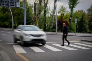 Pedestrian walking on zebra crossing and a driving car failing to stop.