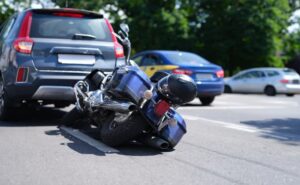 Blue motorcycle lying on road near car . Road traffic accidents with motorcyclists